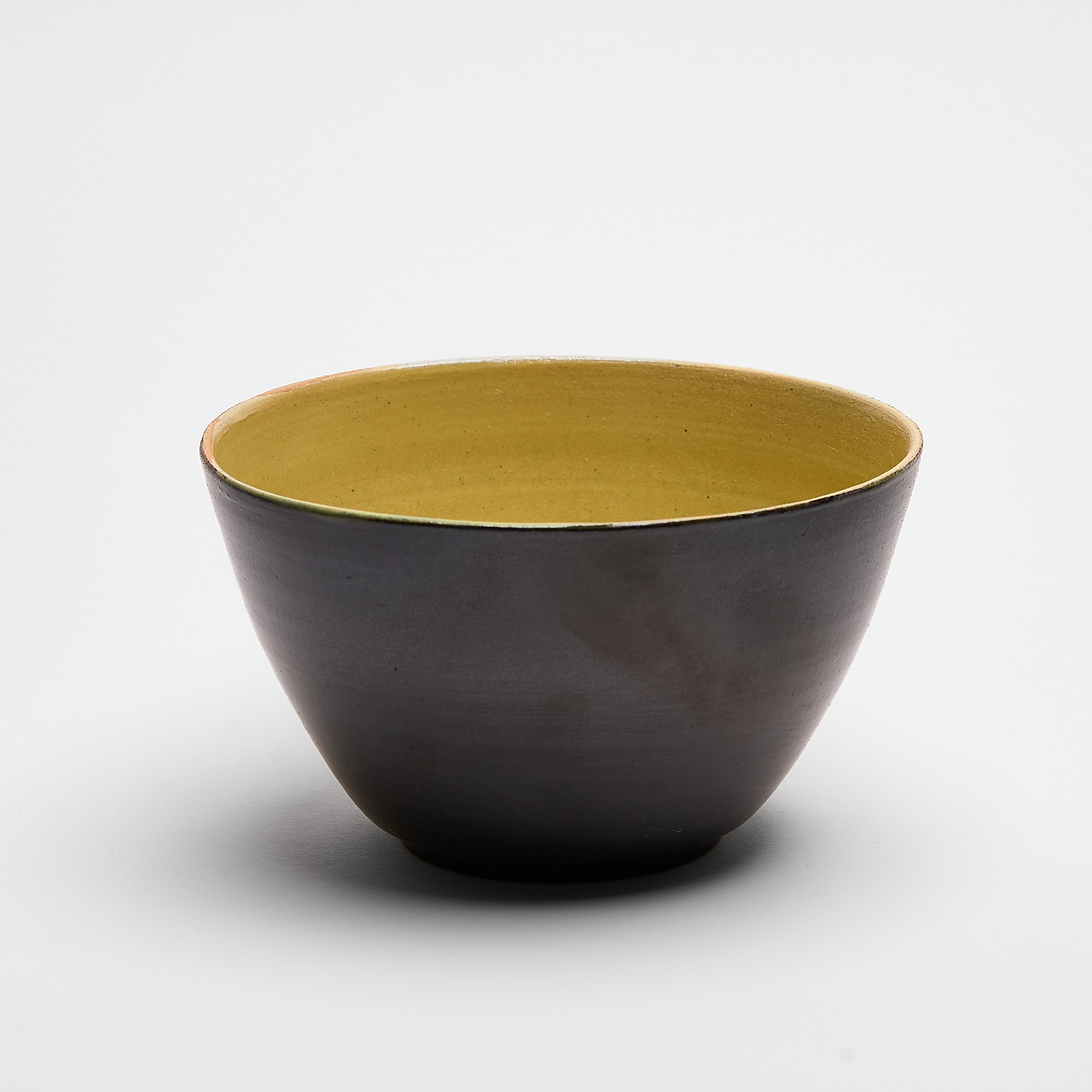 Handgefertigte Keramikschale aus Steinzeug mit schwarzer Außenseite und gelber Innenglasur, hergestellt in Basel